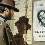 bounty hunter clint eastwood looks at a wanted poster in the western movie for a few dollars more